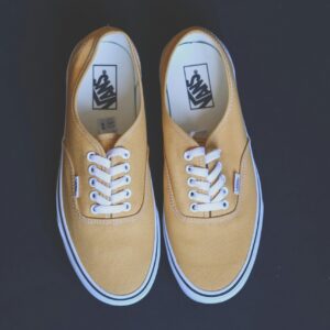 Pair of stylish yellow sneakers on a black background showcasing fashion and footwear design.