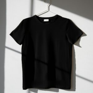 Minimalist image of a black t-shirt on a hanger with dramatic shadows on a white wall.